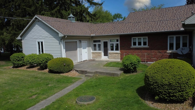 ranch-style home with a front lawn, a shingled roof, and a garage