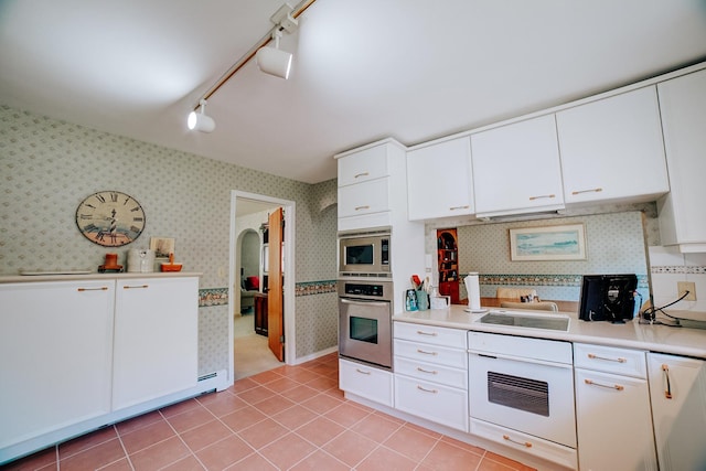 kitchen featuring wallpapered walls, track lighting, white cabinetry, light countertops, and appliances with stainless steel finishes
