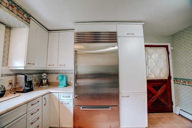 kitchen featuring stainless steel built in refrigerator, white cabinets, wallpapered walls, and a baseboard heating unit