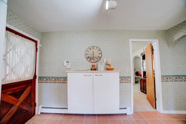 interior space featuring arched walkways, light tile patterned floors, baseboard heating, and wallpapered walls