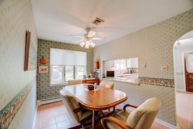 dining space featuring a ceiling fan, baseboard heating, light tile patterned floors, visible vents, and arched walkways