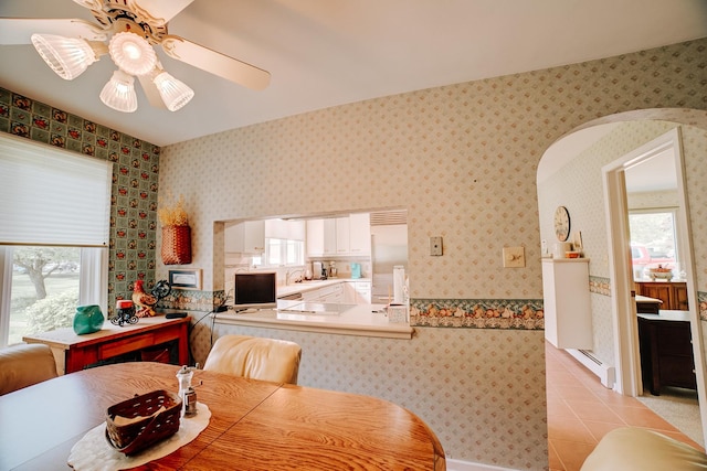 dining area with baseboard heating, ceiling fan, light tile patterned floors, and wallpapered walls