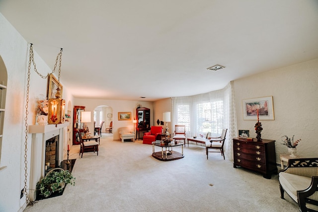 living area featuring visible vents, a fireplace, arched walkways, and carpet floors