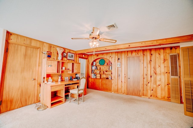 carpeted home office featuring wooden walls, a ceiling fan, and visible vents