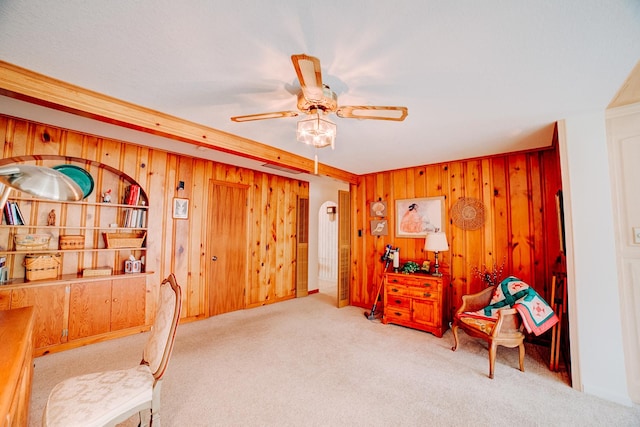 home office featuring wood walls, carpet floors, and a ceiling fan