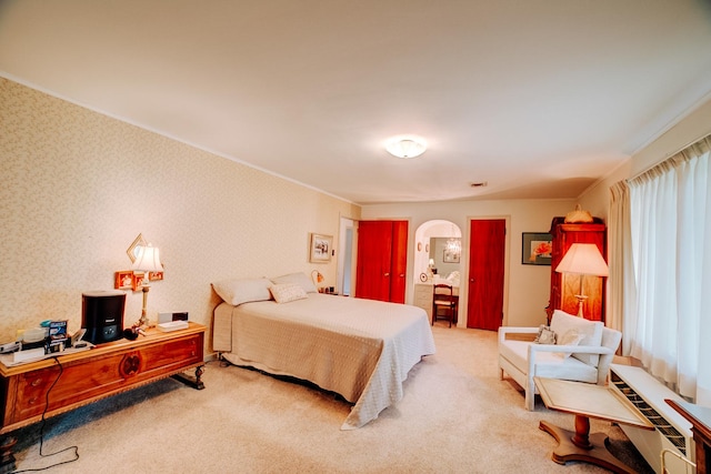 carpeted bedroom featuring ornamental molding and arched walkways