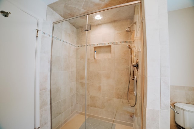 bathroom featuring tile walls, toilet, and a stall shower