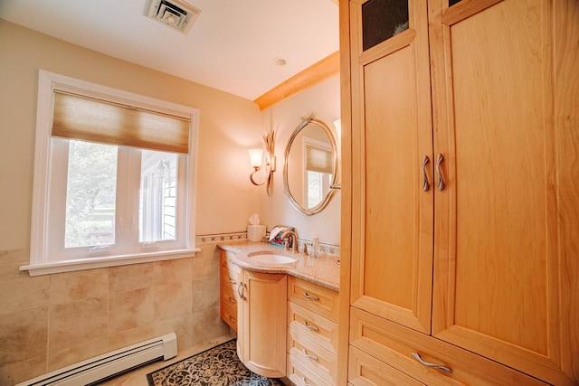 bathroom with tile walls, vanity, visible vents, a baseboard radiator, and wainscoting