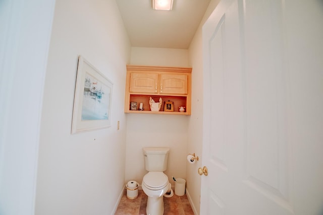 bathroom with toilet, baseboards, and tile patterned flooring