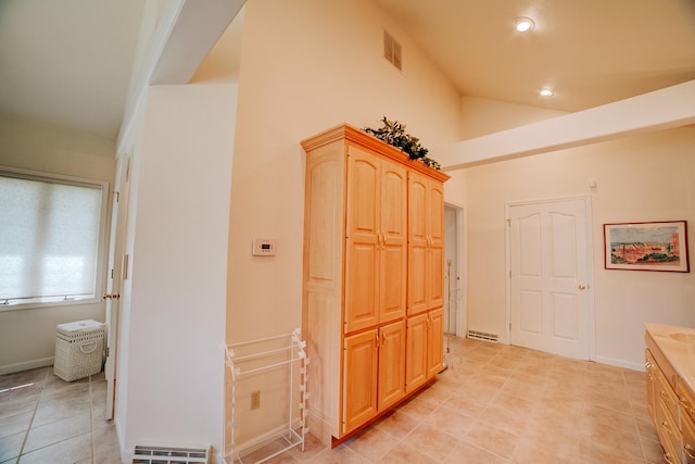 hallway with high vaulted ceiling, light tile patterned floors, visible vents, and recessed lighting