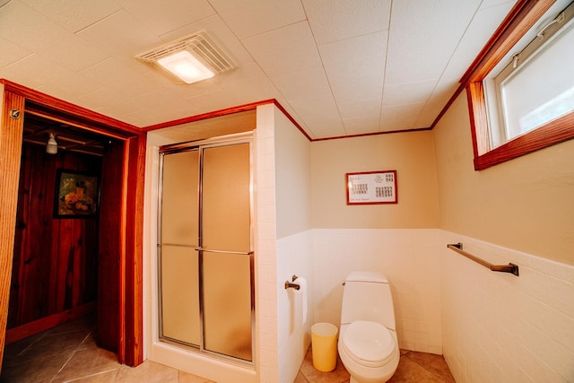 bathroom featuring a stall shower, a wainscoted wall, visible vents, and tile patterned floors