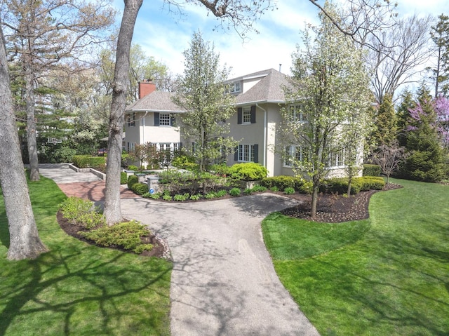 view of home's community with curved driveway and a yard