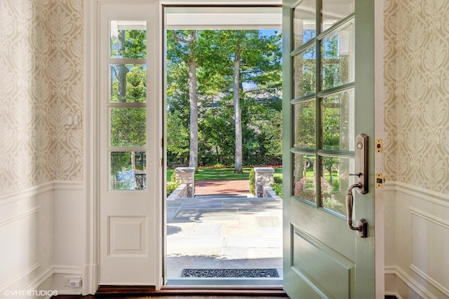 entryway featuring wallpapered walls, wainscoting, and a decorative wall