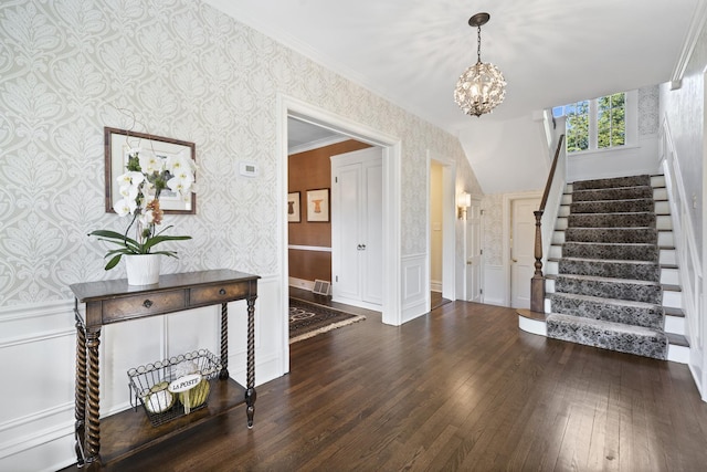 entryway with wallpapered walls, a chandelier, stairway, wainscoting, and wood-type flooring