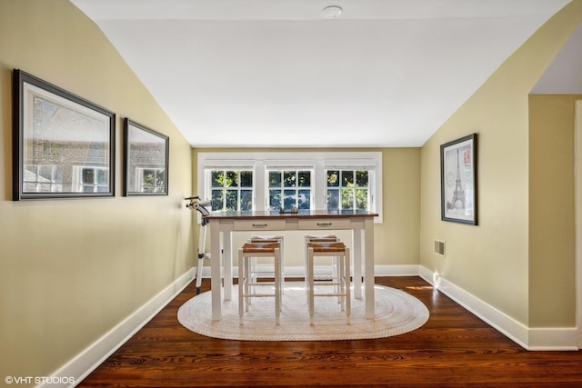 dining space featuring vaulted ceiling, dark wood-style flooring, and baseboards
