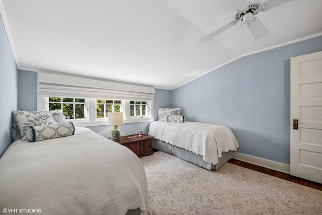 bedroom featuring crown molding, lofted ceiling, wood finished floors, baseboards, and a ceiling fan