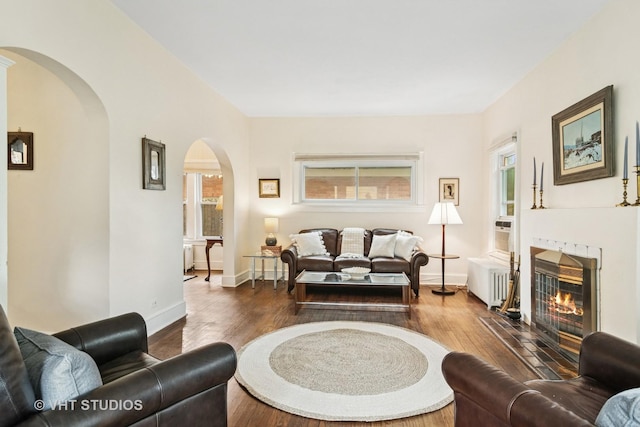 625 Greenbriar Ln, Lake Forest, IL 60045 - living room featuring arched walkways, a tiled fireplace, dark wood-type flooring, baseboards, and radiator