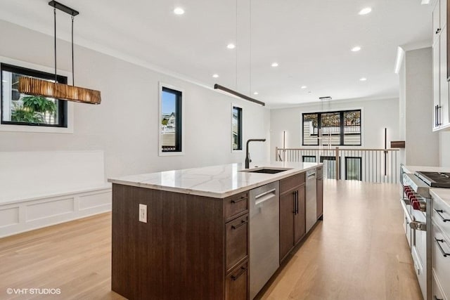 1928 W George St, Chicago, IL 60657 - kitchen featuring stainless steel appliances, dark brown cabinets, light wood-style floors, a center island with sink, and decorative light fixtures