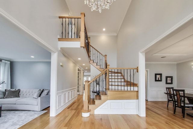 living room featuring a chandelier, stairway, wood finished floors, a decorative wall, and wainscoting