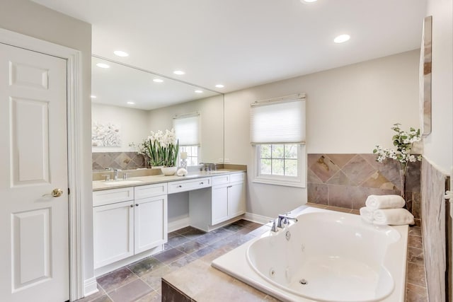 bathroom featuring double vanity, recessed lighting, and a tub with jets