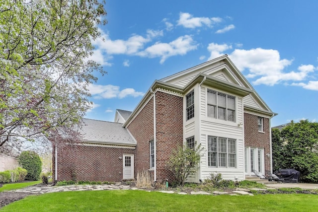 view of home's exterior featuring brick siding, a yard, and entry steps