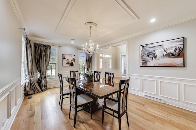 dining room with a decorative wall, a chandelier, a tray ceiling, crown molding, and light wood-style floors