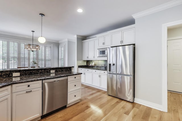 kitchen featuring appliances with stainless steel finishes, ornamental molding, white cabinetry, decorative backsplash, and light wood-type flooring