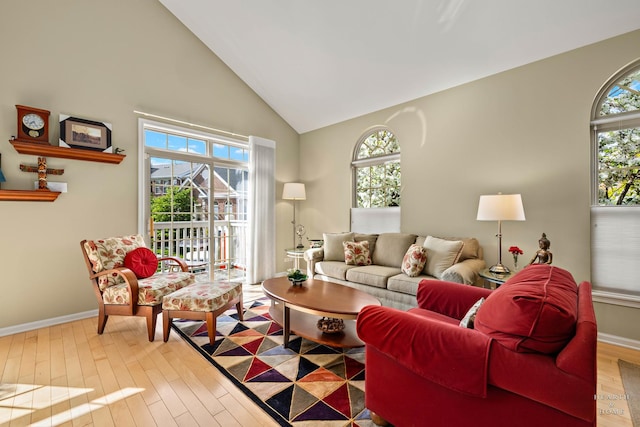 living area with high vaulted ceiling, wood finished floors, and baseboards