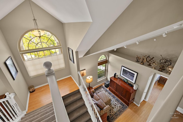 stairway with wood finished floors, healthy amount of natural light, and high vaulted ceiling