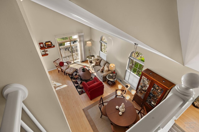 living area featuring high vaulted ceiling, wood finished floors, and baseboards