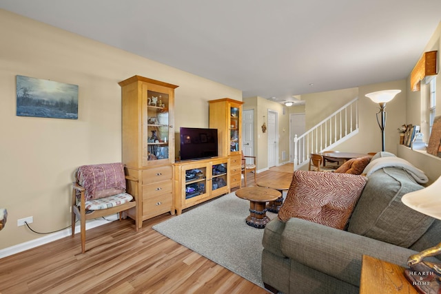 living area with stairway, light wood-style floors, and baseboards