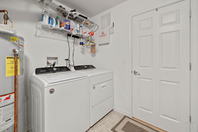 washroom featuring water heater, washing machine and dryer, and light tile patterned floors