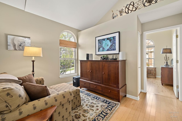 sitting room with baseboards, light wood-style flooring, and high vaulted ceiling
