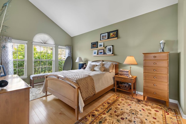 bedroom with wood finished floors and high vaulted ceiling