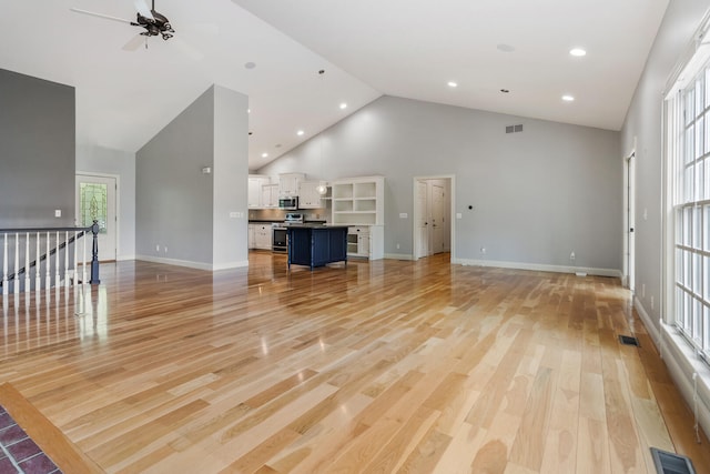 unfurnished living room with high vaulted ceiling, light wood-style flooring, ceiling fan, baseboards, and recessed lighting