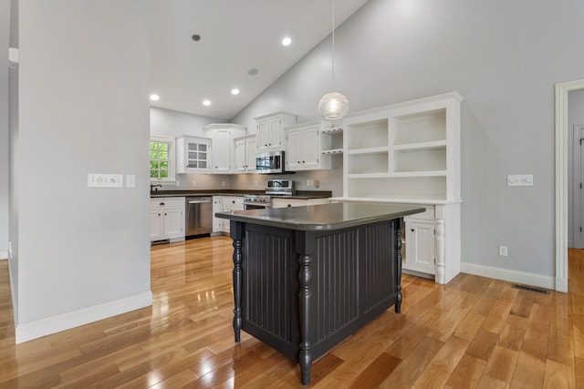 kitchen featuring appliances with stainless steel finishes, open shelves, dark countertops, white cabinetry, and high vaulted ceiling