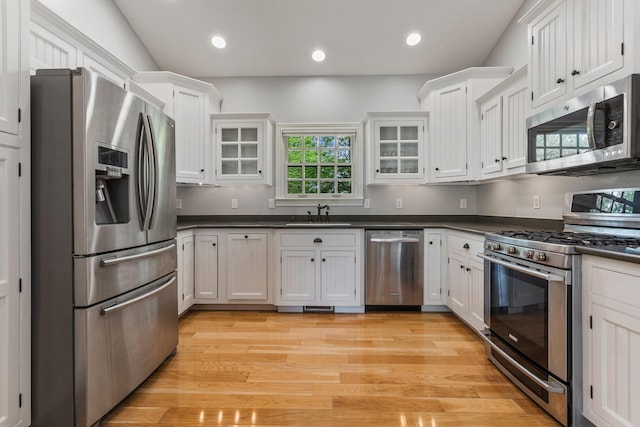kitchen featuring stainless steel appliances, dark countertops, light wood-type flooring, white cabinetry, and recessed lighting