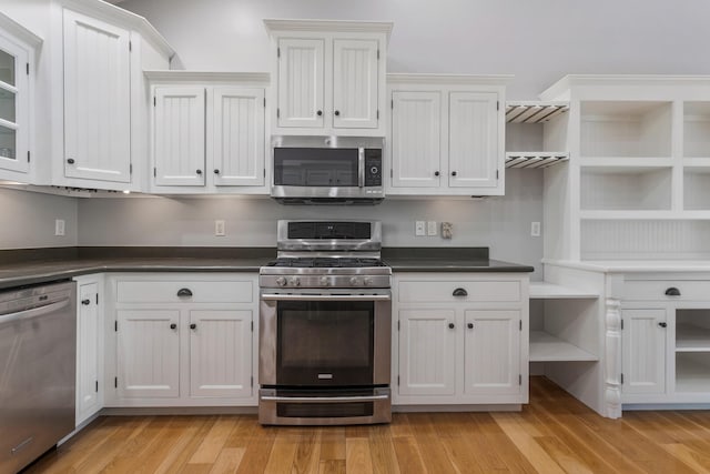 kitchen with appliances with stainless steel finishes, open shelves, white cabinets, and dark countertops