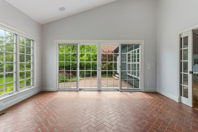 unfurnished room with brick flooring, high vaulted ceiling, plenty of natural light, and baseboards