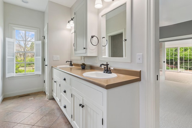 full bathroom featuring healthy amount of natural light, baseboards, and double vanity