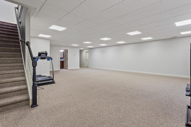 basement featuring carpet flooring, a paneled ceiling, stairway, and baseboards