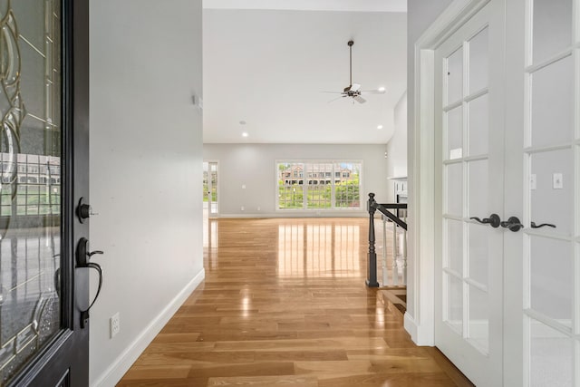 hallway with light wood-style flooring, baseboards, and high vaulted ceiling