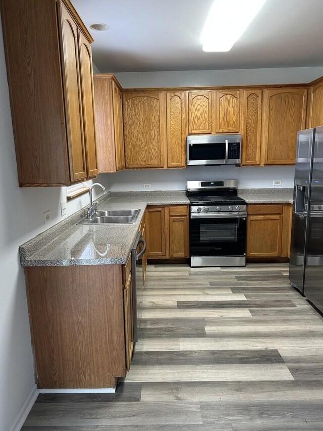 272 Aspen Cir, Gilberts, IL 60136 - kitchen with appliances with stainless steel finishes, a sink, light wood-style floors, and brown cabinetry