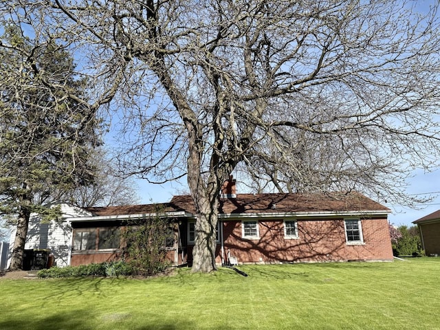 9450 Greenwood Ave, Des Plaines, IL 60016 - rear view of property with a yard, a chimney, brick siding, and a sunroom
