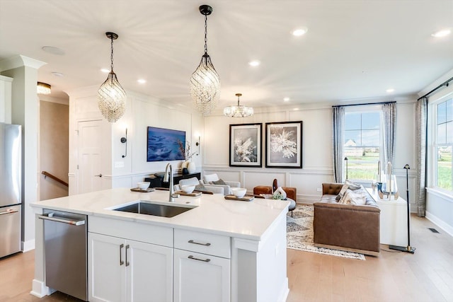 kitchen featuring light wood-style floors, open floor plan, white cabinets, a sink, and stainless steel appliances