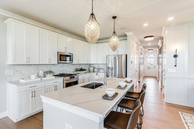 kitchen with backsplash, a kitchen bar, appliances with stainless steel finishes, light wood-type flooring, and a sink