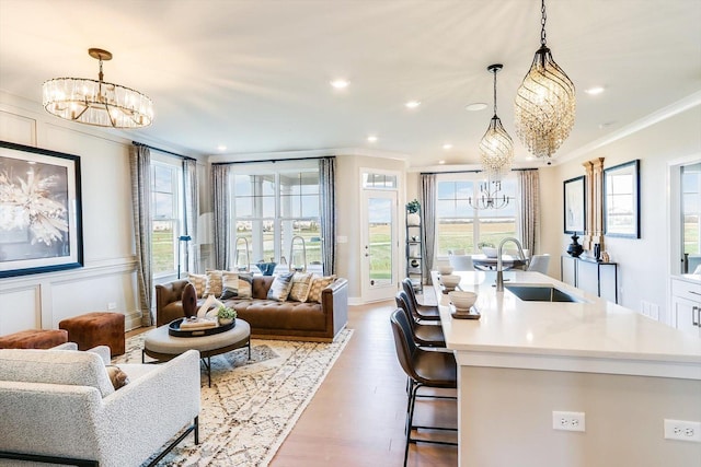 living room with crown molding, recessed lighting, a notable chandelier, and wood finished floors