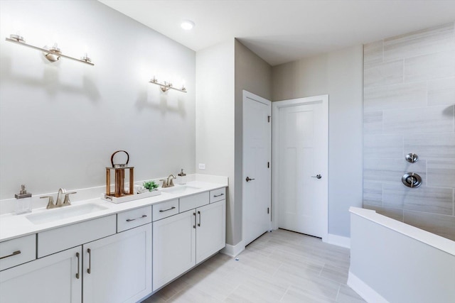 bathroom featuring baseboards, a sink, a tile shower, and double vanity