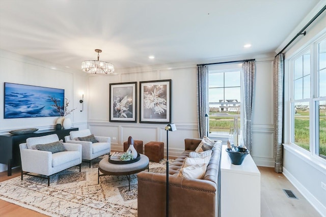 living area featuring an inviting chandelier, a decorative wall, light wood-style flooring, recessed lighting, and visible vents