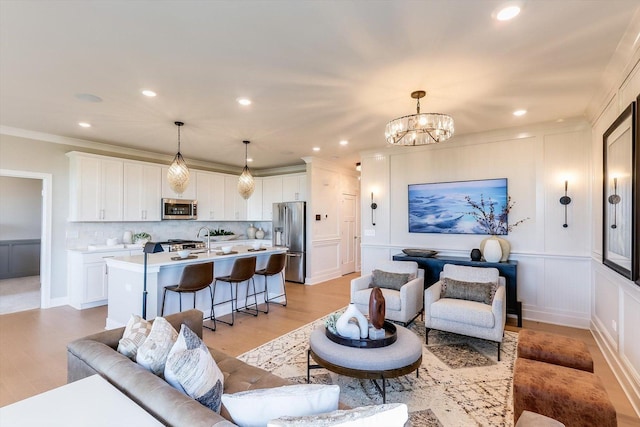 living room featuring crown molding, recessed lighting, an inviting chandelier, and a decorative wall